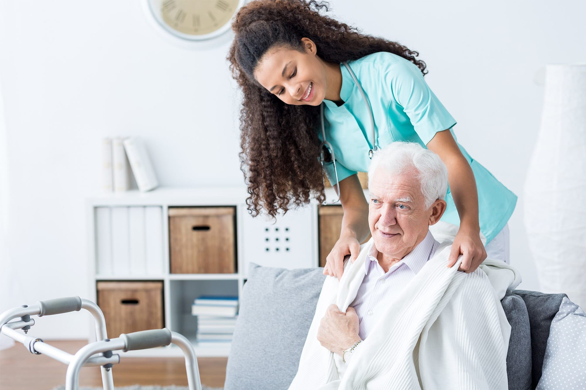 A caregiver assists an elderly man with a blanket in a cozy living space, emphasizing the importance of compassionate support in healthcare.